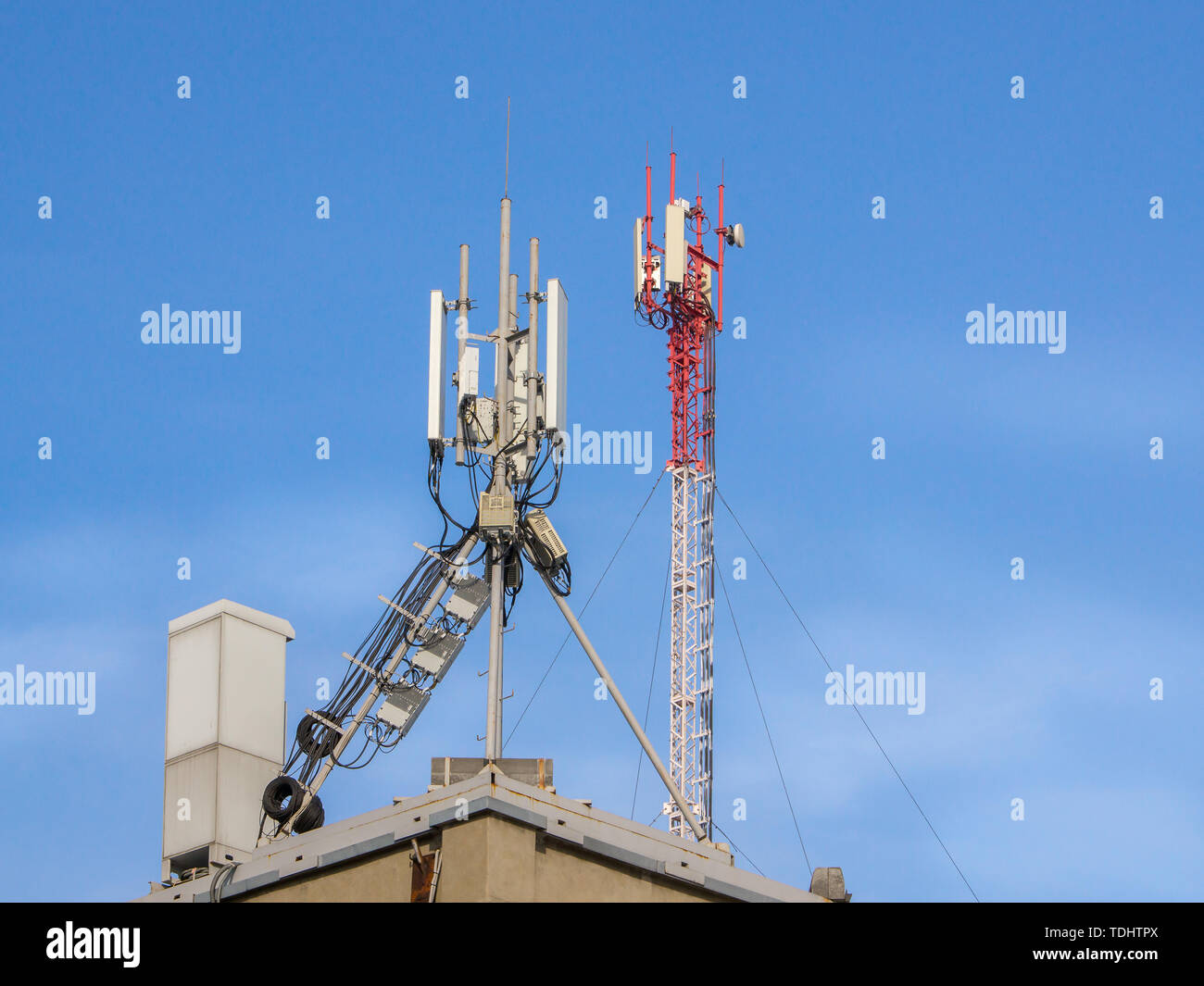 The cellular communication aerial on a building roof. Cell phone telecommunication tower. Antennas on top of building Stock Photo