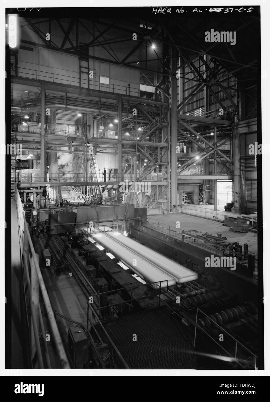 OVERVIEW LOOKING SOUTH OF CONTAINMENT SYSTEM (TOP), SLAB CASTING MACHINE AND RUN OUT WITH TRAVELING TORCH. MACHINE IS CASTING IN TWIN MOLD. - U.S. Steel, Fairfield Works, Continuous Caster, Fairfield, Jefferson County, AL Stock Photo