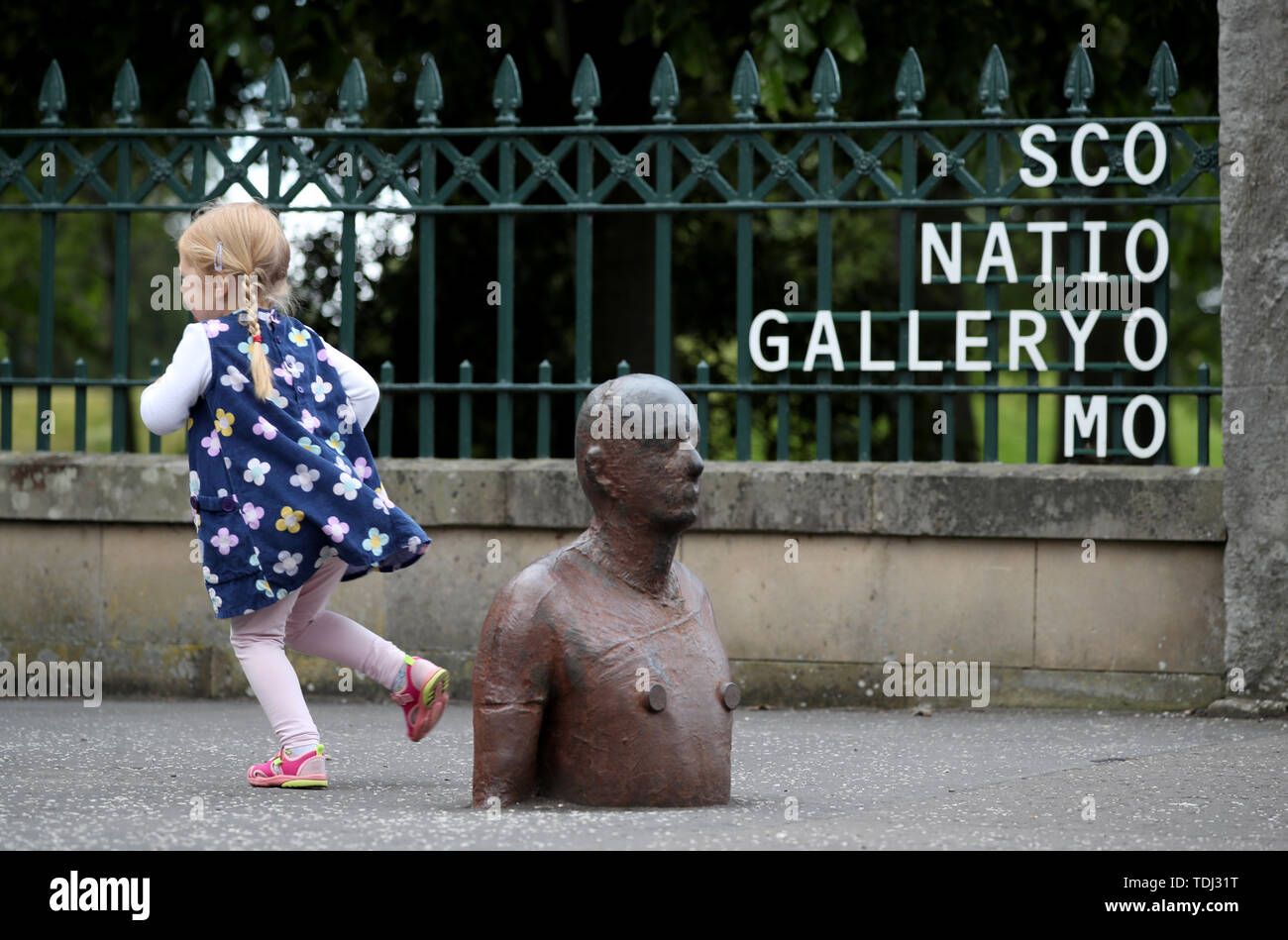 Phoebo Chisholm, 3, runs past 'Goma Man' one of six life-size iron figures by artist Antony Gormley that forms part of the installation '6 Times' which marks out a watery route along Edinburgh's Water of Leith from the Scottish National Gallery of Modern Art to the sea at Leith Docks. Stock Photo