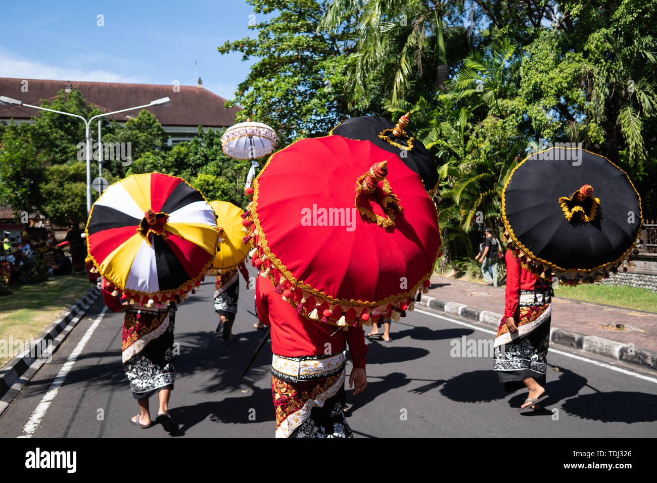 Group of Balinese dancer in ethnic costumes with traditional colorful umbrellas on hindu ceremony parade during temple festival. Balinese people cultu Stock Photo