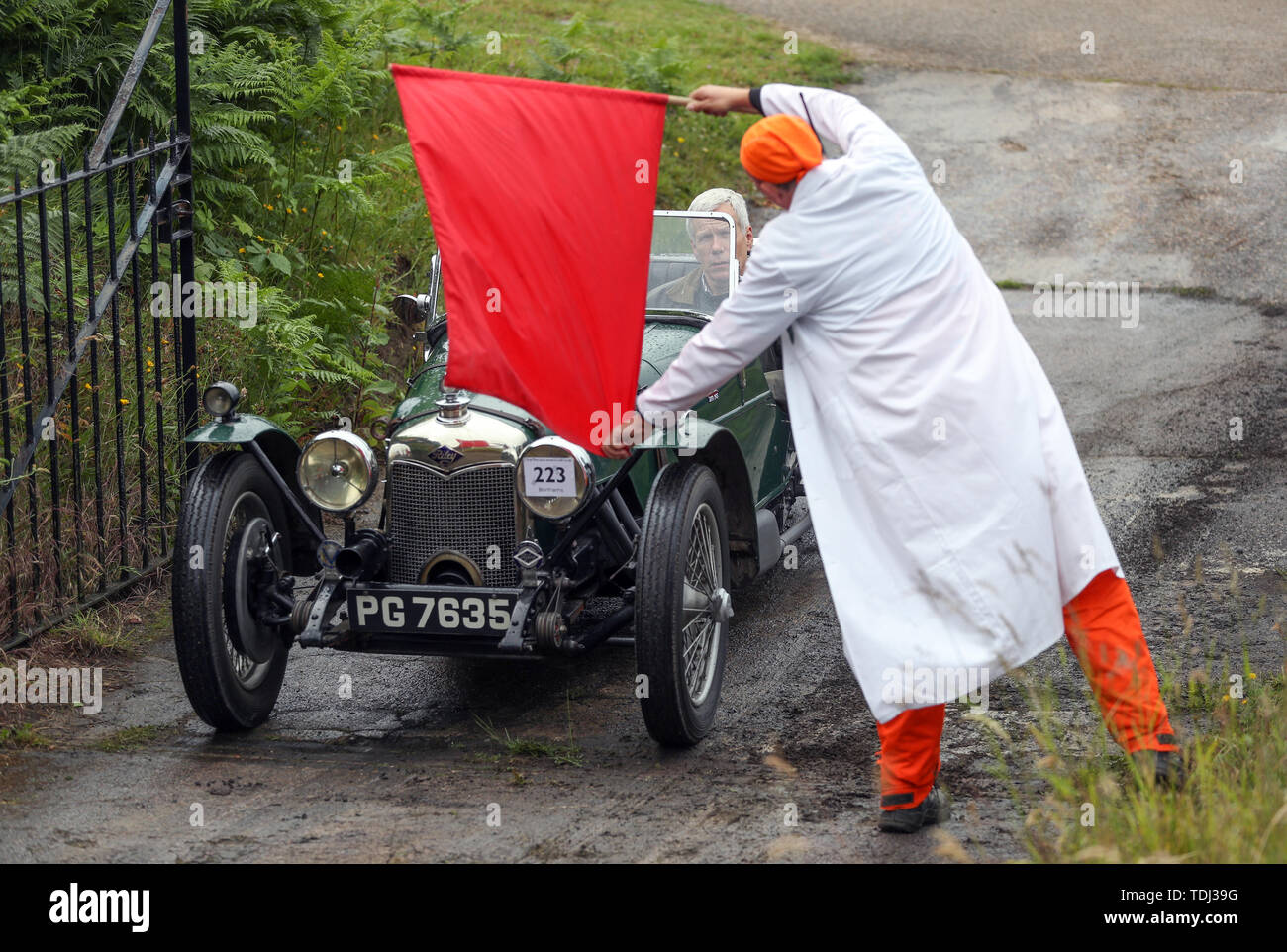 A marshall waves off the driver of a 1930 Riley Brooklands, as it takes on the hill test during the Brooklands Double Twelve Motorsport Festival at Brooklands Museum, in Weybridge, Surrey. Stock Photo