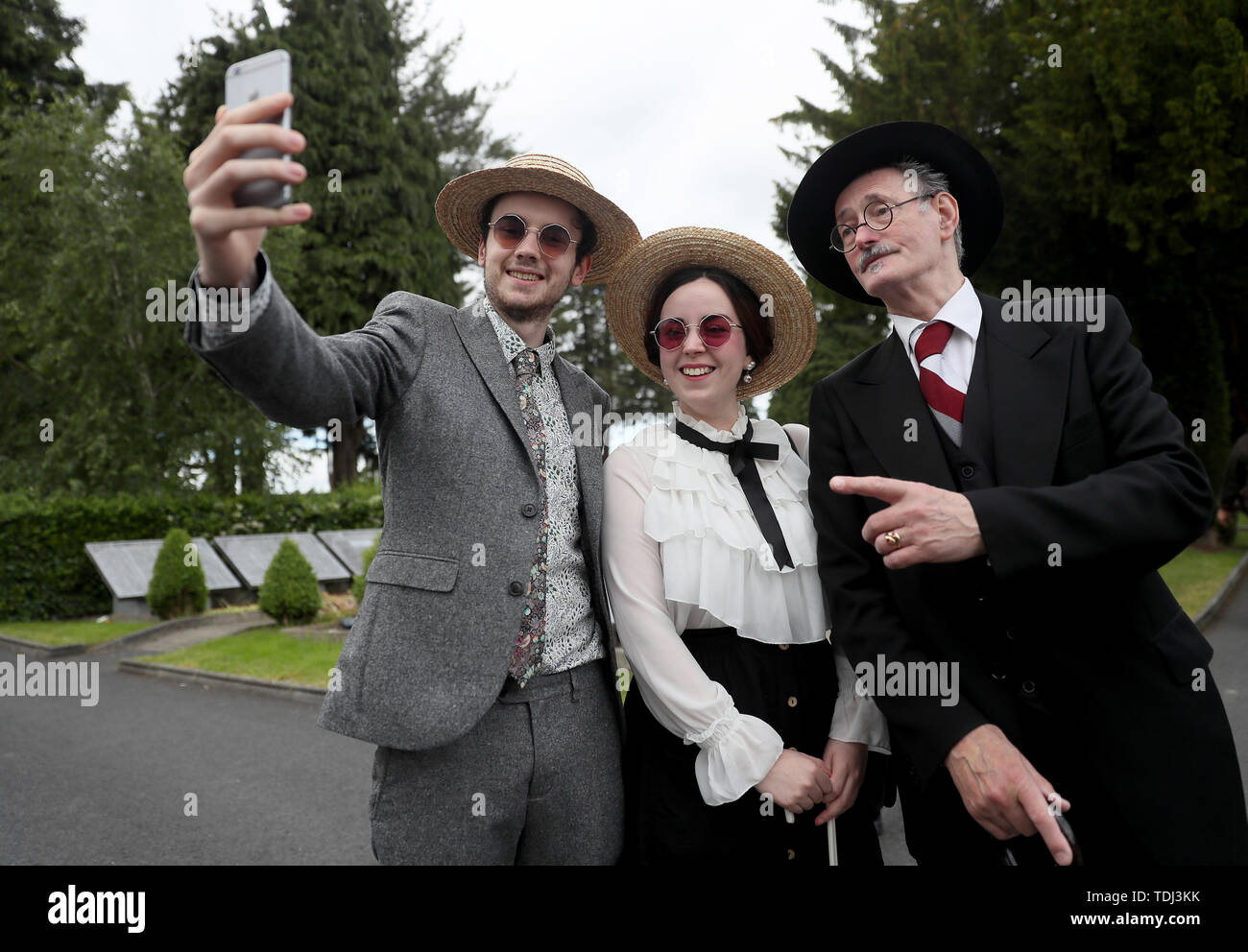 Failan O'Mahoney, from Rathgar, and Roisin Byrne, from Phibsboro, pose for a selfie with James Joyce lookalike John Shevlin, at the annual Bloomsday event at Glasnevin Cemetery, Dublin, featuring a reenactment from the 'Hades' chapter of James Joyce's Ulysses. Stock Photo