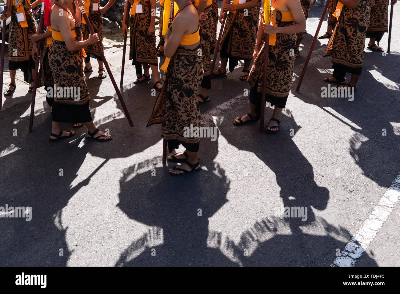 Shadow of the group of Balinese dancer in ethnic costumes with traditional colorful umbrellas on hindu ceremony parade during temple festival. Balines Stock Photo