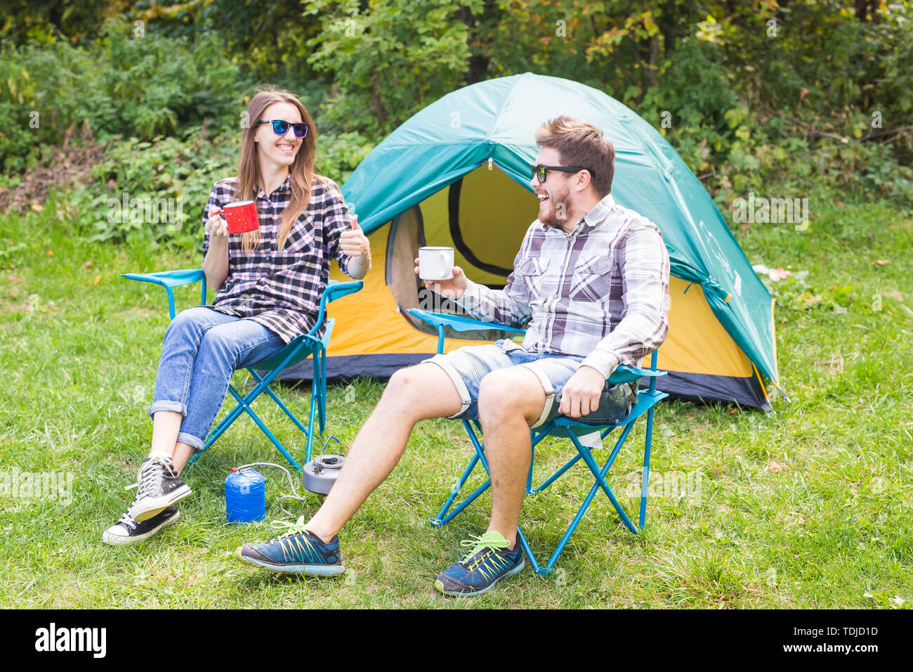 people, summer tourism and nature concept - young couple sitting near a ...