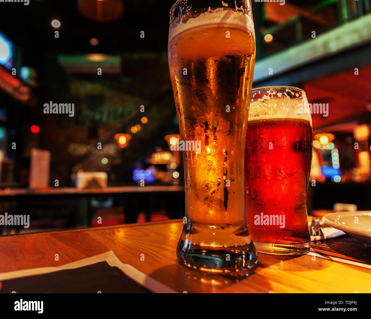 Glasses of light and dark beer on a pub background. Atmospheric twilight setting in the bar. Stock photo Stock Photo