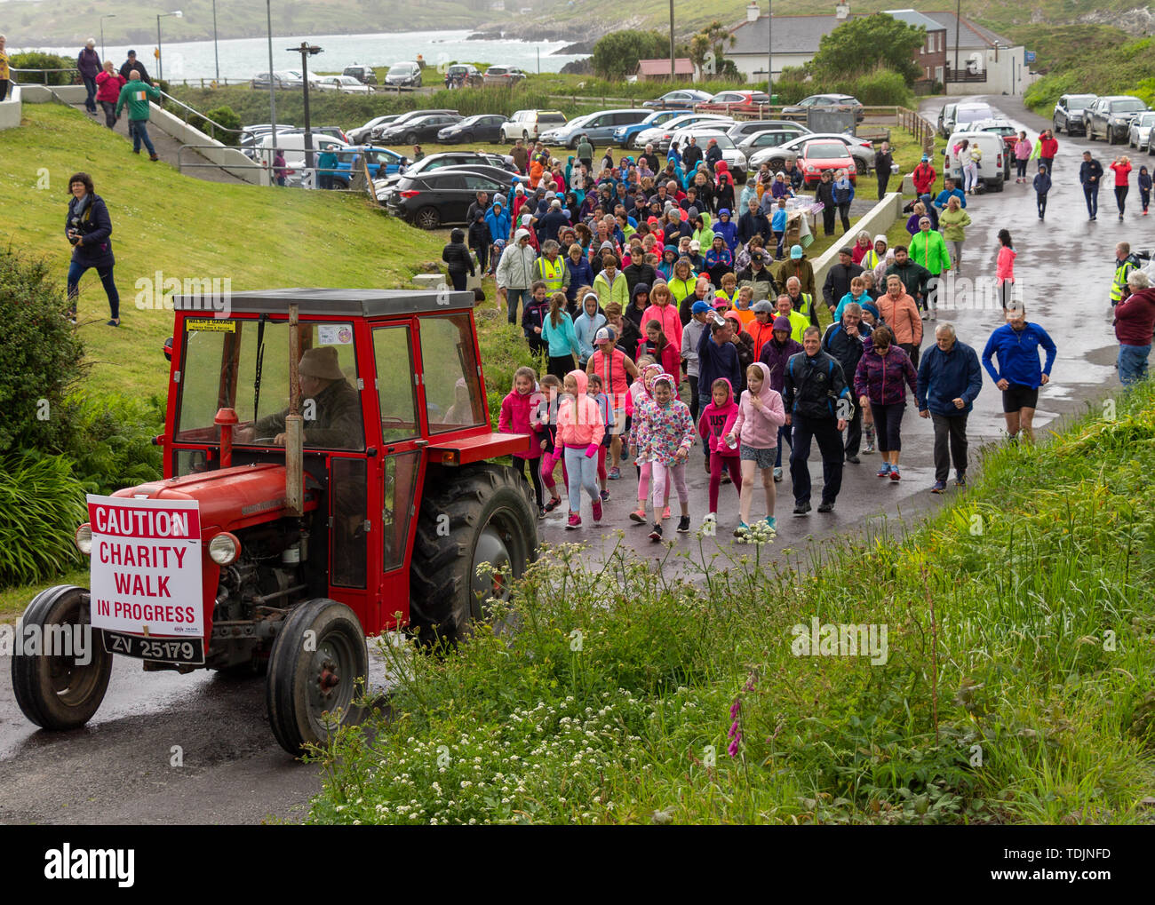 Red Massey Ferguson tractor leading a crowd of people on a charity walk Stock Photo