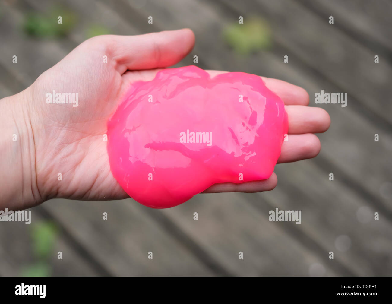 Pink anti stress toy slime in hand. Fighting anxiety and stress. Creative game experiment for children. Stock Photo