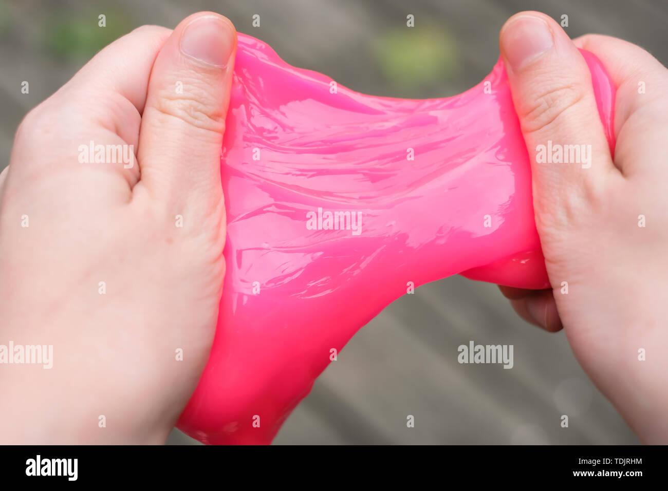 Pink anti stress toy slime in hands. Fighting anxiety and stress. Creative game experiment for children. Stock Photo