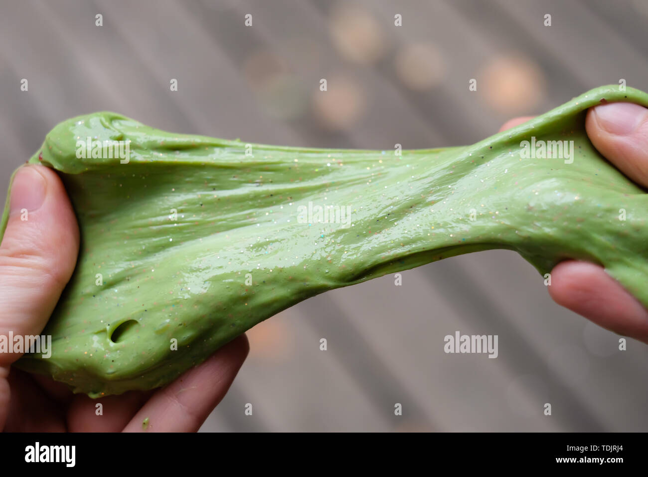 Green anti stress toy slime with glitter in hands. Fighting anxiety and