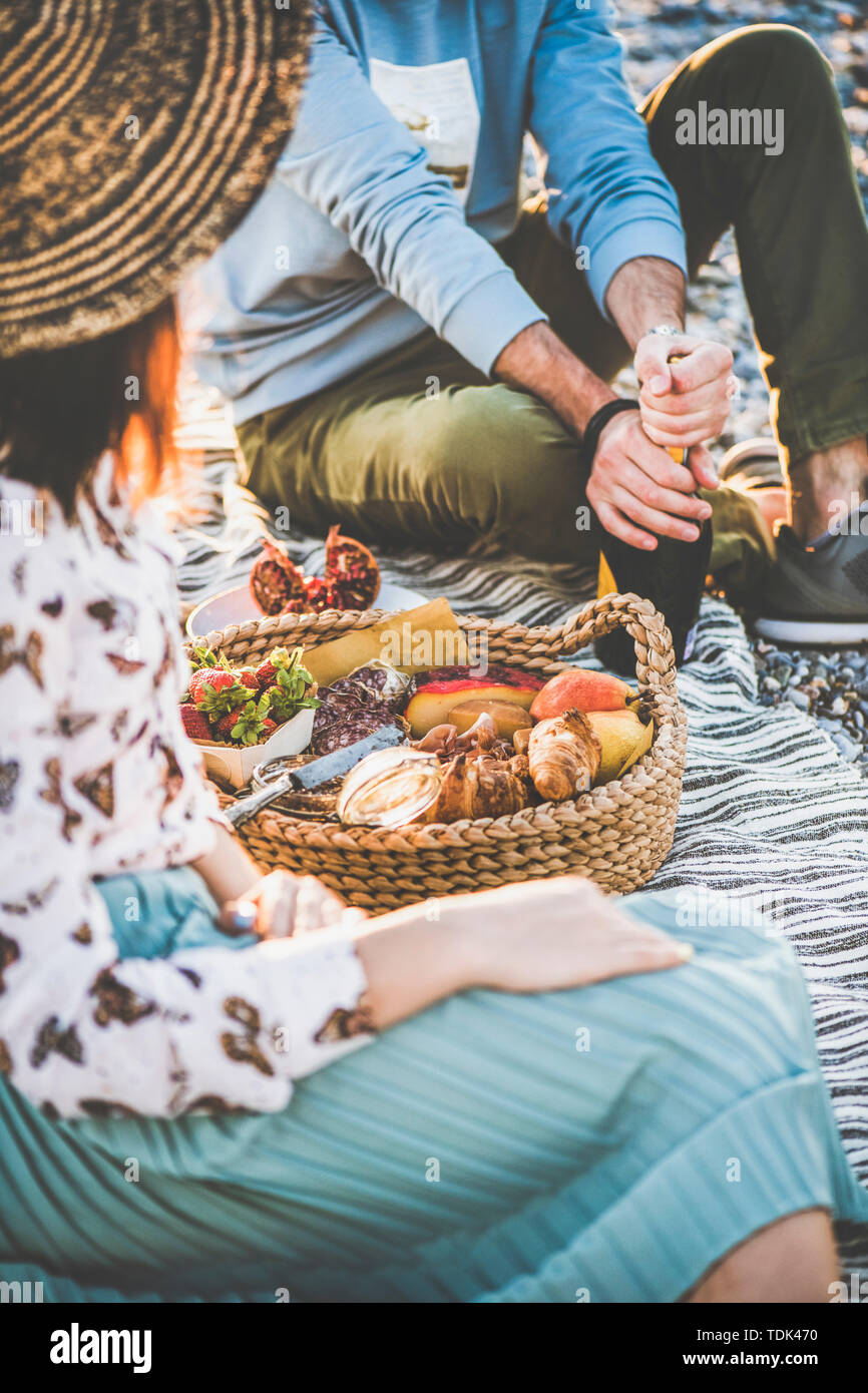 Summer beach picnic at sunset. Young couple having weekend picnic