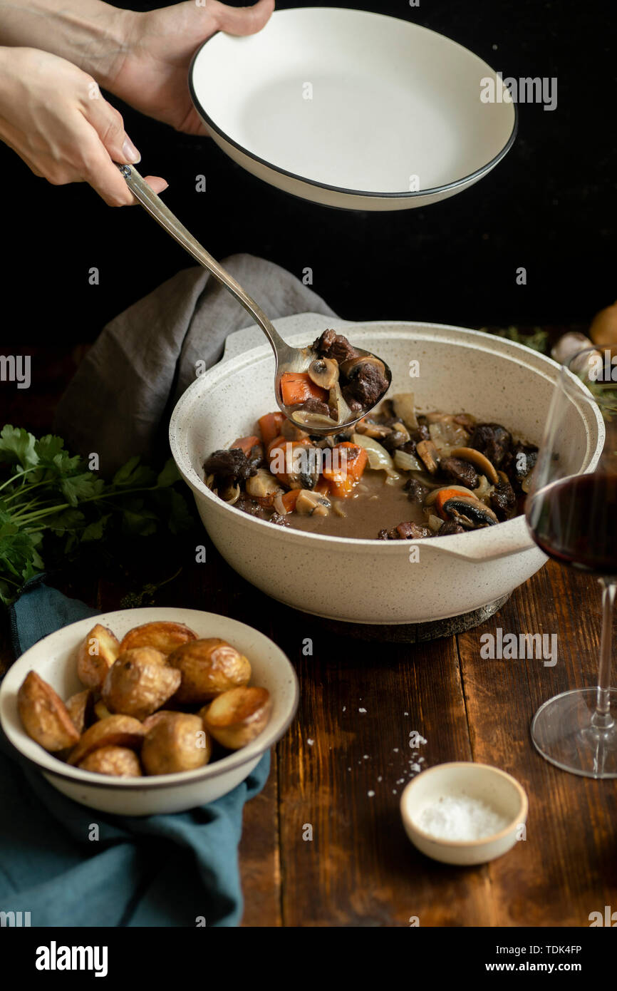 Female hand serving boeuf bourgignon traditional french beef stew Stock Photo Alamy