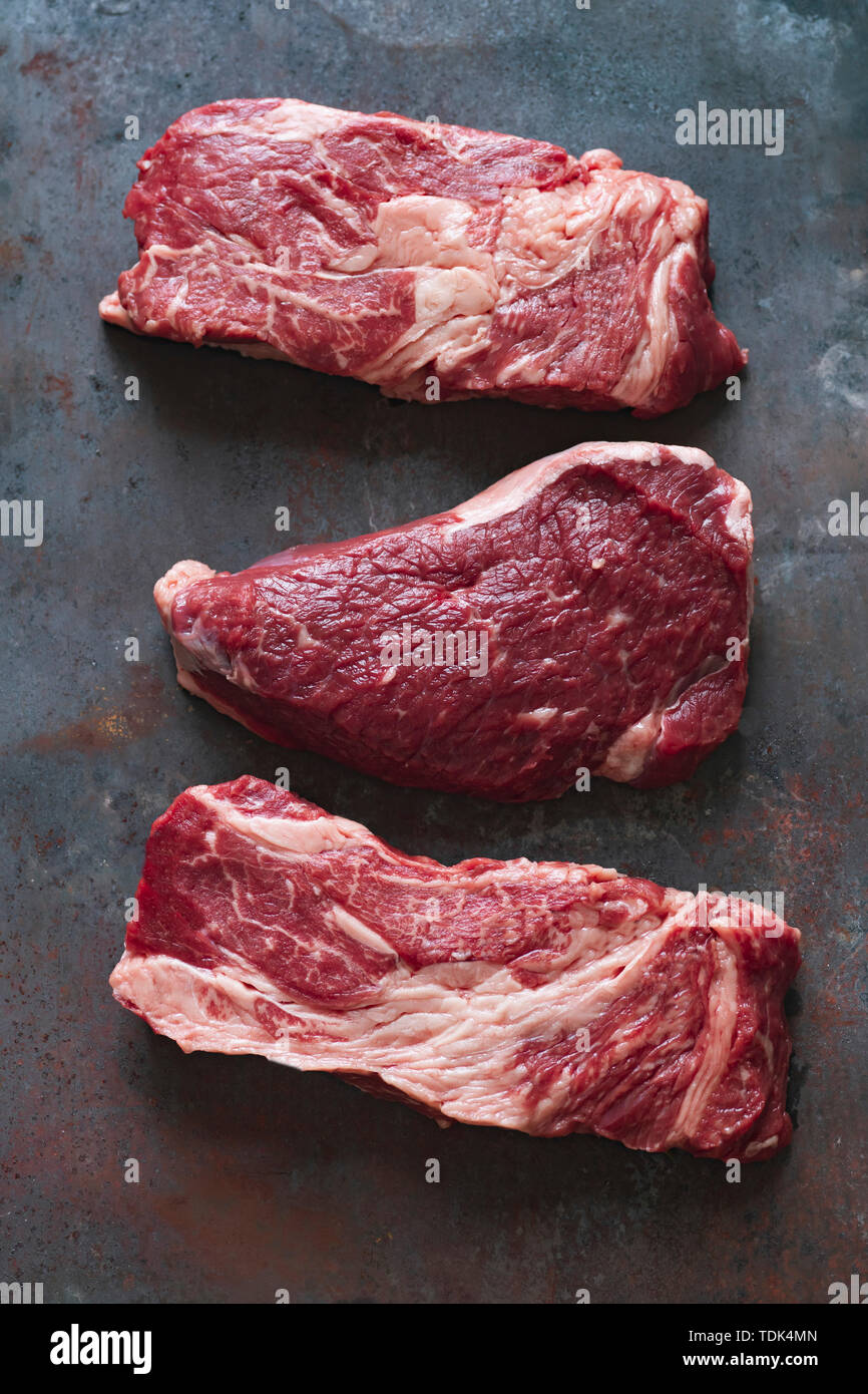 Raw black angus prime beef steak variety on dark metallic background Stock Photo