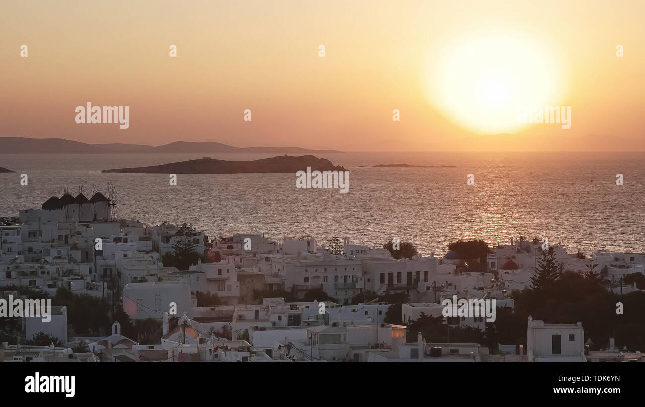 the sun sets behind the popular tourist town of chora on mykonos, greece Stock Photo