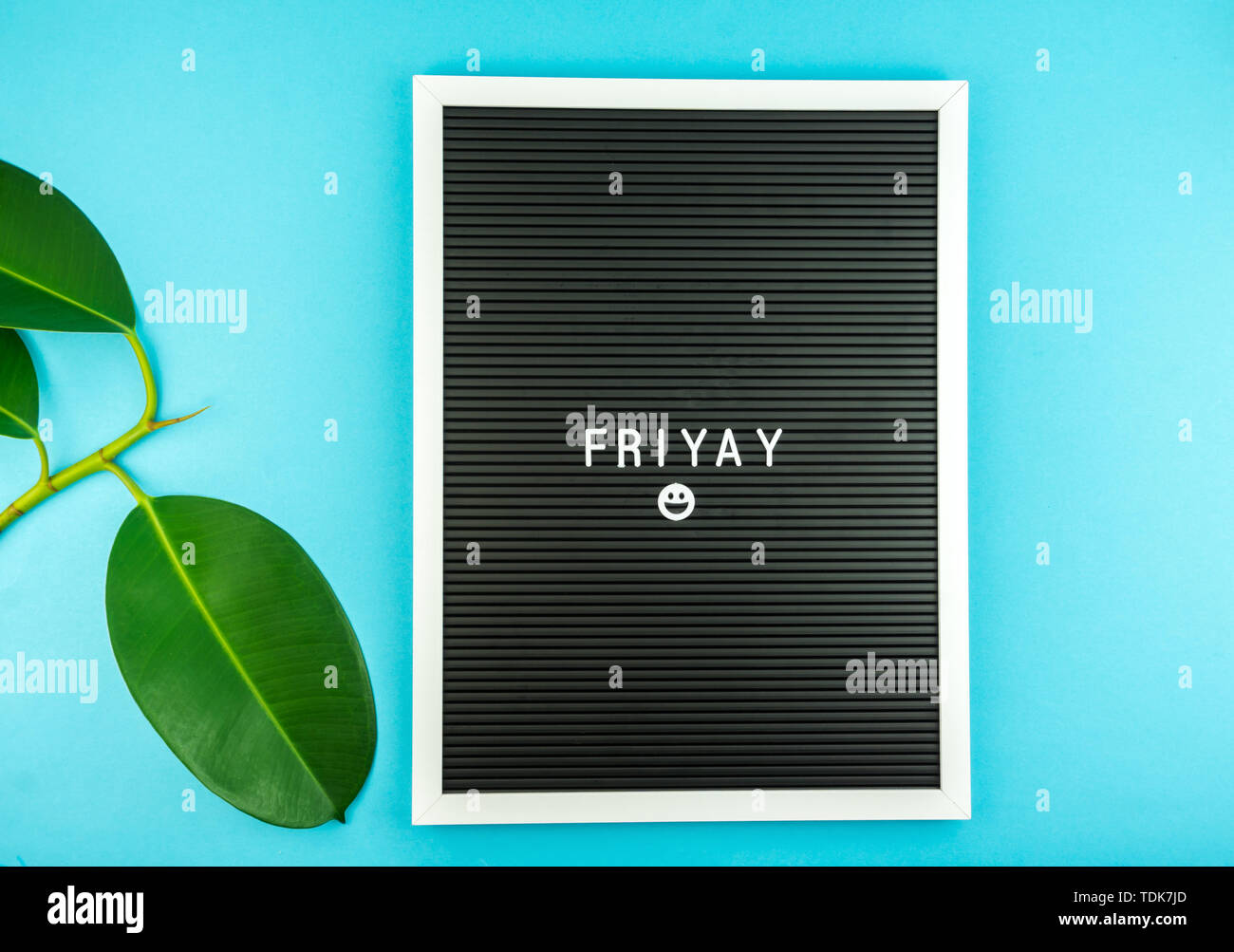 The word FRIDAY on a letter board with happy smiley emoji against blue background Stock Photo