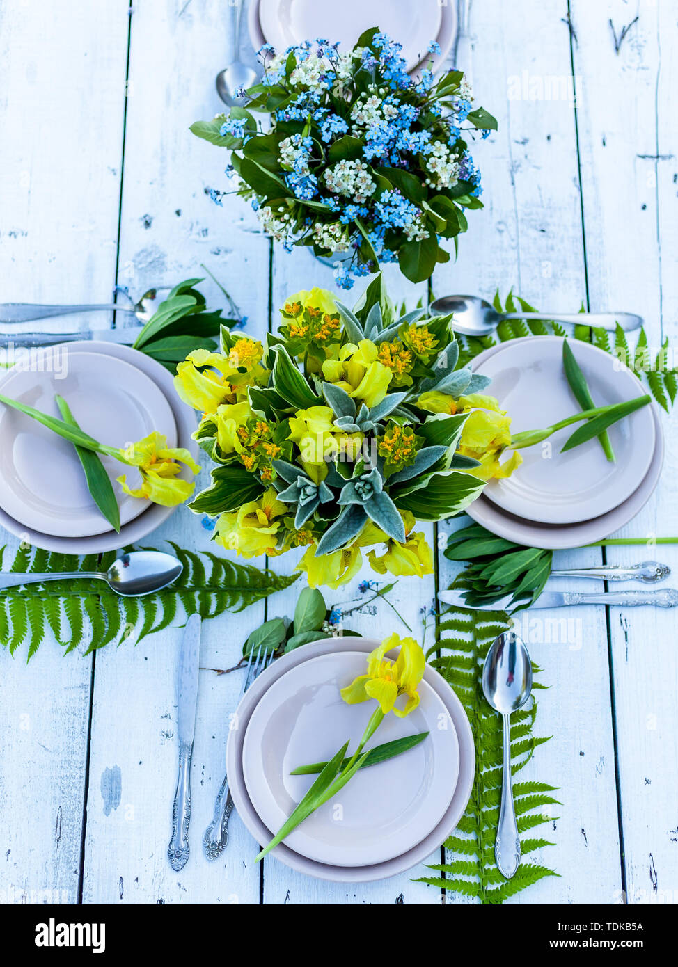 Wedding decoration in rustic style. Florist design. Bouquets of irises and forget-me-nots. Outdoor Wedding. Top view Stock Photo