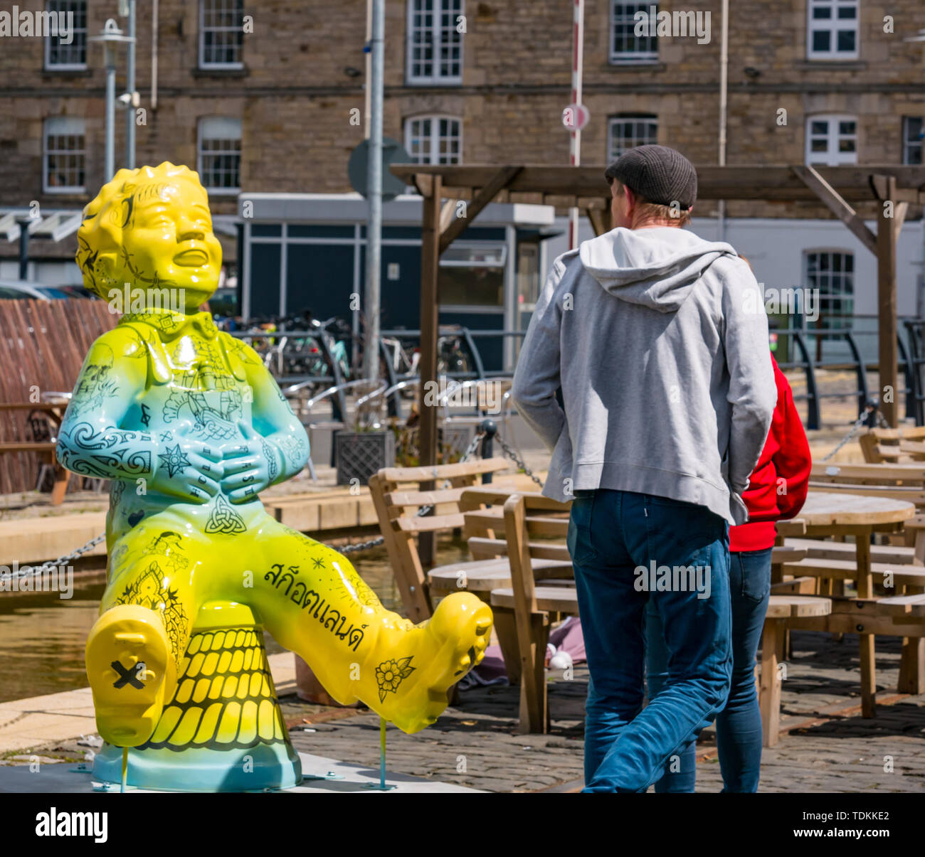 Leith, Edinburgh, Scotland, United Kingdom, 17 June 2019. Oor Wullie's Big Bucket Trail: An art trail of 200 Oor Wullie sculptures appear in Scottish cities in a mass arts event that lasts until August 30th. Oor Wullie is an iconic Scottish cartoon character from the Sunday Post newspaper. The sculptures will be auctioned to raise money for Scotland’s children’s hospital charities. There are 5 in the Leith area, and 60 in Edinburgh altogether.  Sailoor Wullie by The Leith Agency with a couple stopping to look Stock Photo