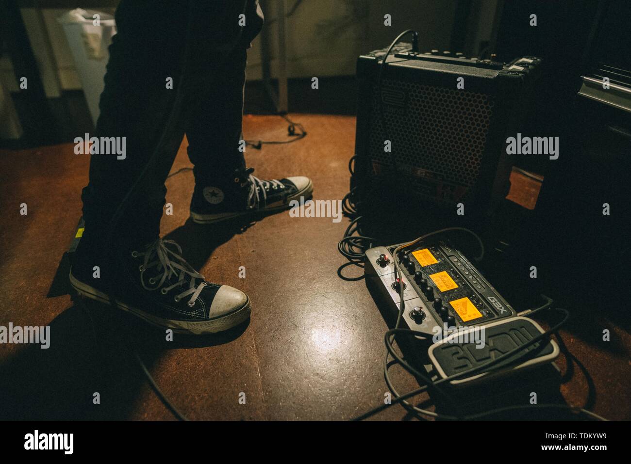 Guitarist's feet with sneakers and a guitar effect processor on the