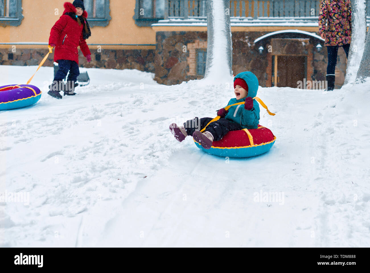 happy child. little boy in winter ride on a sled from the mountain. Kid long and happy smiles and have fun. Stock Photo