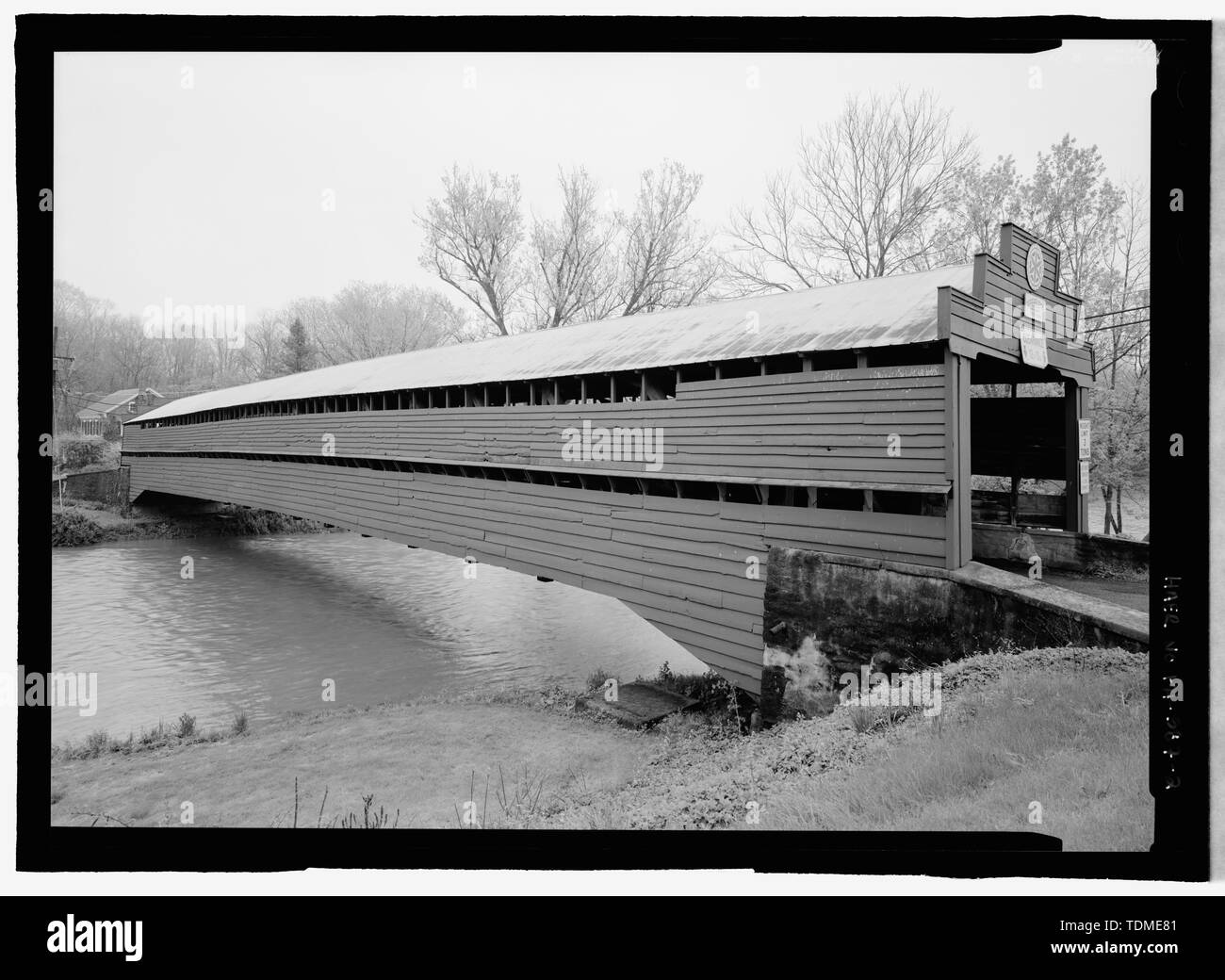 PERSPECTIVE WITH WEST PORTAL. THE BRIDGE IS CLAD IN HORIZONTAL CLAPBOARD SIDING AND HAS A SHEET METAL ROOF. NOTE THE TWO OPENINGS THAT RUN THE LENGTH OF THE BRIDGE; ONE IS AT THE EAVES AND THE OTHER IS ABOUT 4' ABOVE THE DECK. - Dreibelbis Station Bridge, Spanning Maiden Creek, Balthaser Road (TR 745), Lenhartsville, Berks County, PA; Dreibelbis, Simon; Kutz, Charles; Burr, Theodore; Palmer, Timothy; Dreibelbis, Manasses; Fisher, Samuel; Stitzel, Charles; Traquair, Adam; Biddle, Owen; Rush, William; Wenwag, Lewis; Nathans, Isaac; Schuylkill and Lehigh Railroad; Genovese, Anthony; Marston, Chri Stock Photo