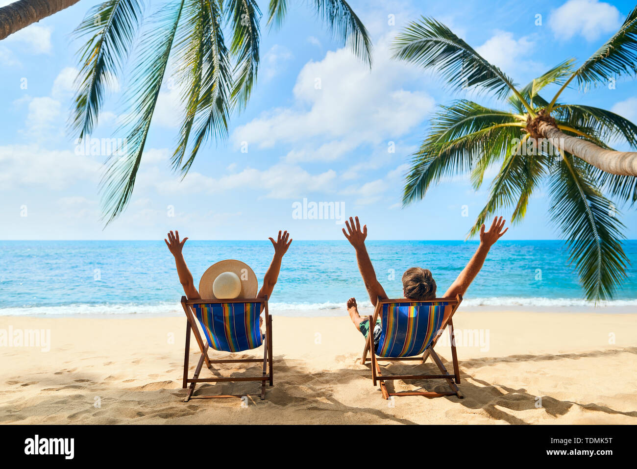 Happy couple with arms up relax on the beach enjoy beautiful sea on the tropical island. Summer beach vacation concept Stock Photo