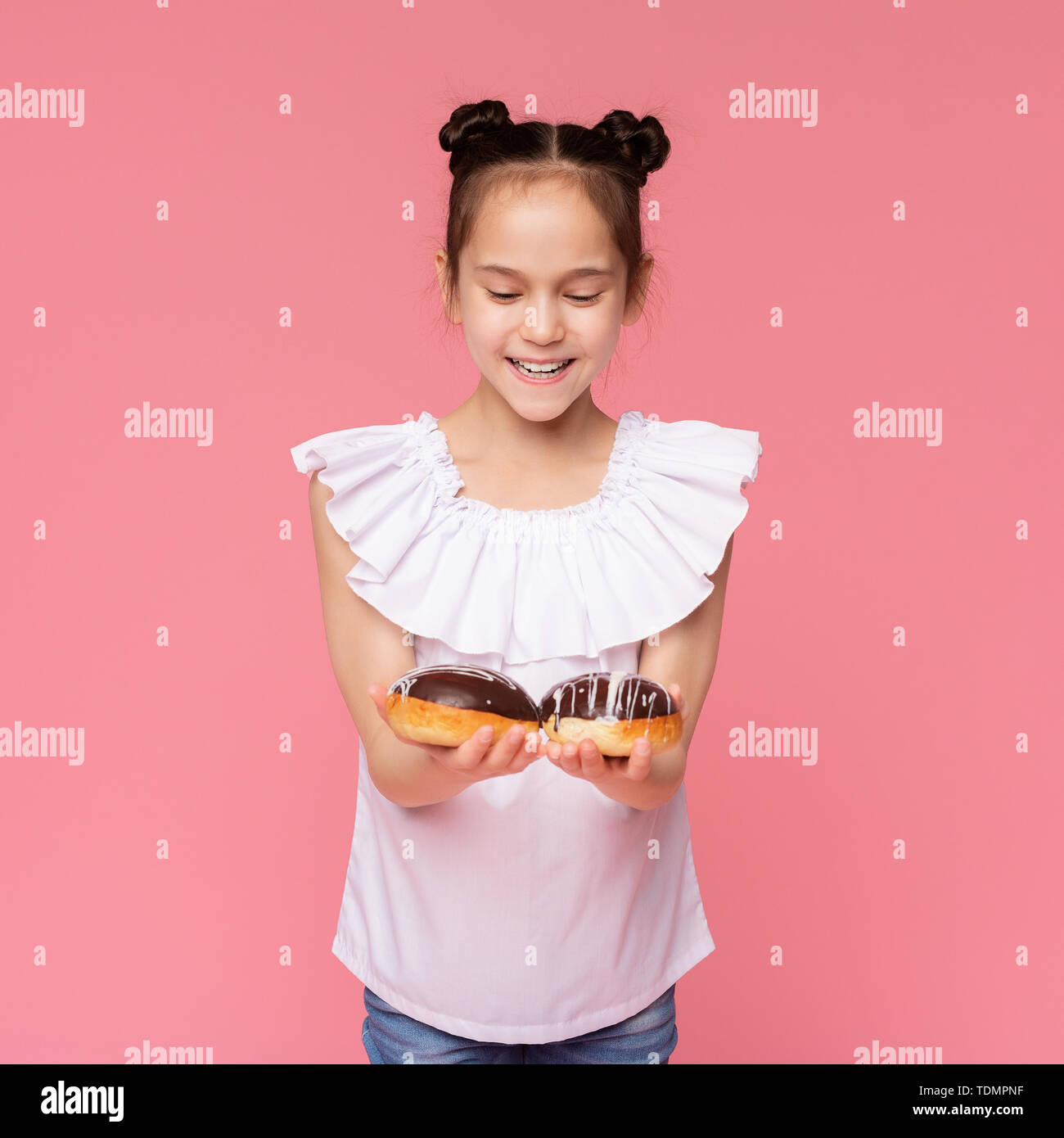 Cheerful little girl enjoying chocolate covered donuts Stock Photo