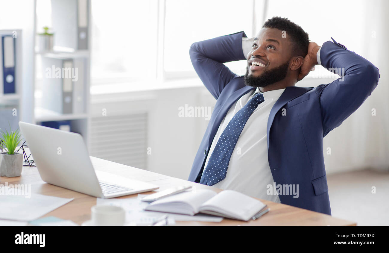 Young african businessman in formalwear relaxing at workplace Stock Photo