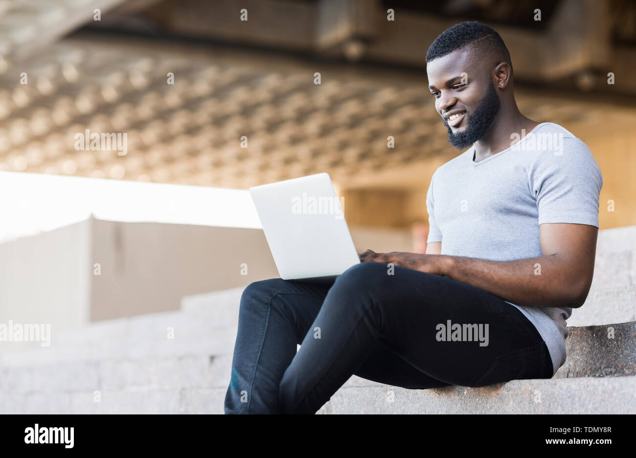 Smiling african american guy coding on his laptop Stock Photo - Alamy
