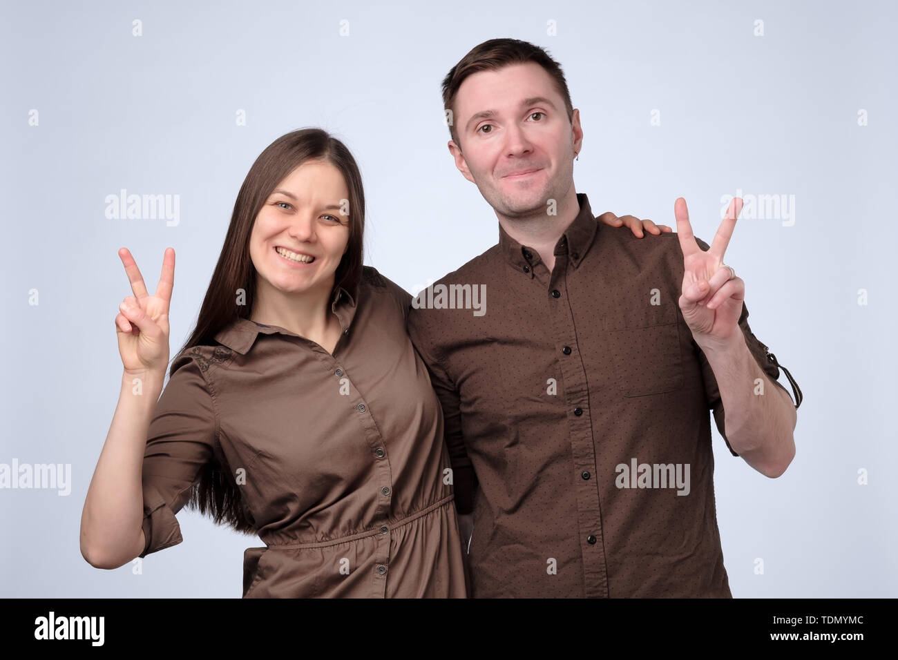 Couple making peace or victory sign with index and middle fingers Stock Photo