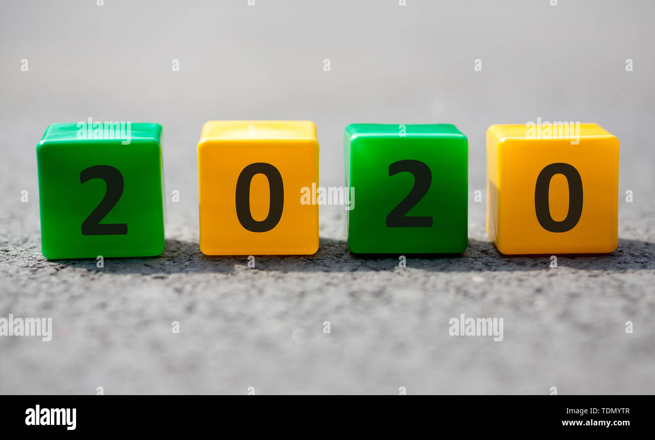 Plastic cubes with 2020 text placed on grey asphalt on the sun Stock Photo