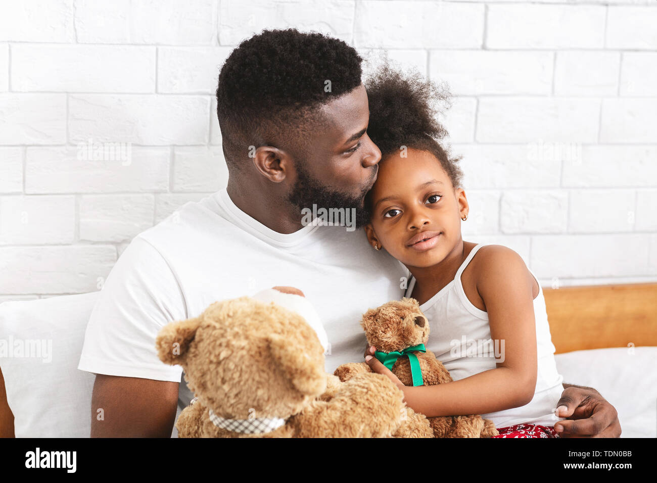 Caring african dad kissing his adorable little daughter in forehead Stock Photo