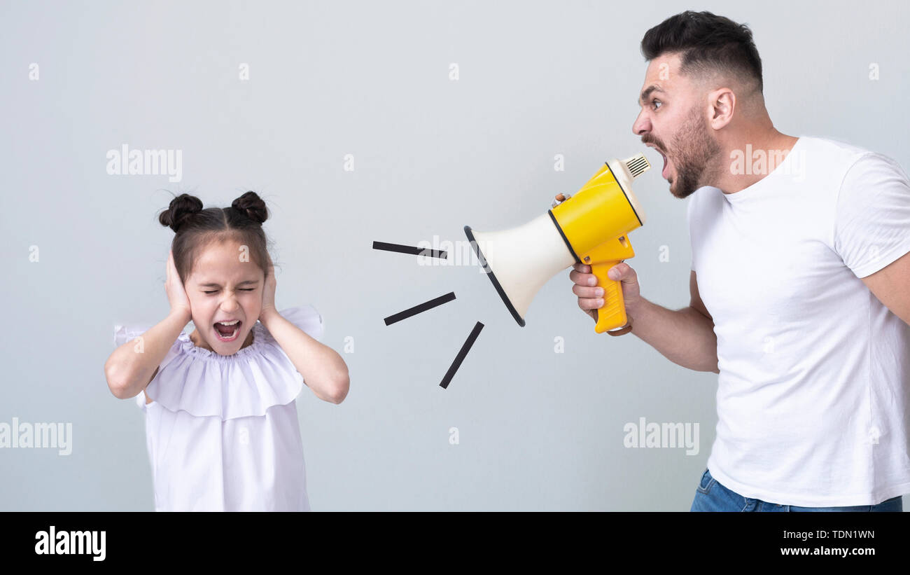 Furious dad screaming at his daughter with megaphone Stock Photo