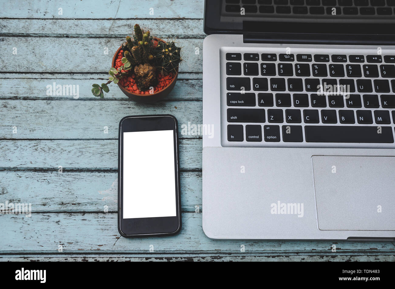 Laptop and smartphone and cactus on a wooden table. Vintage tone Stock Photo