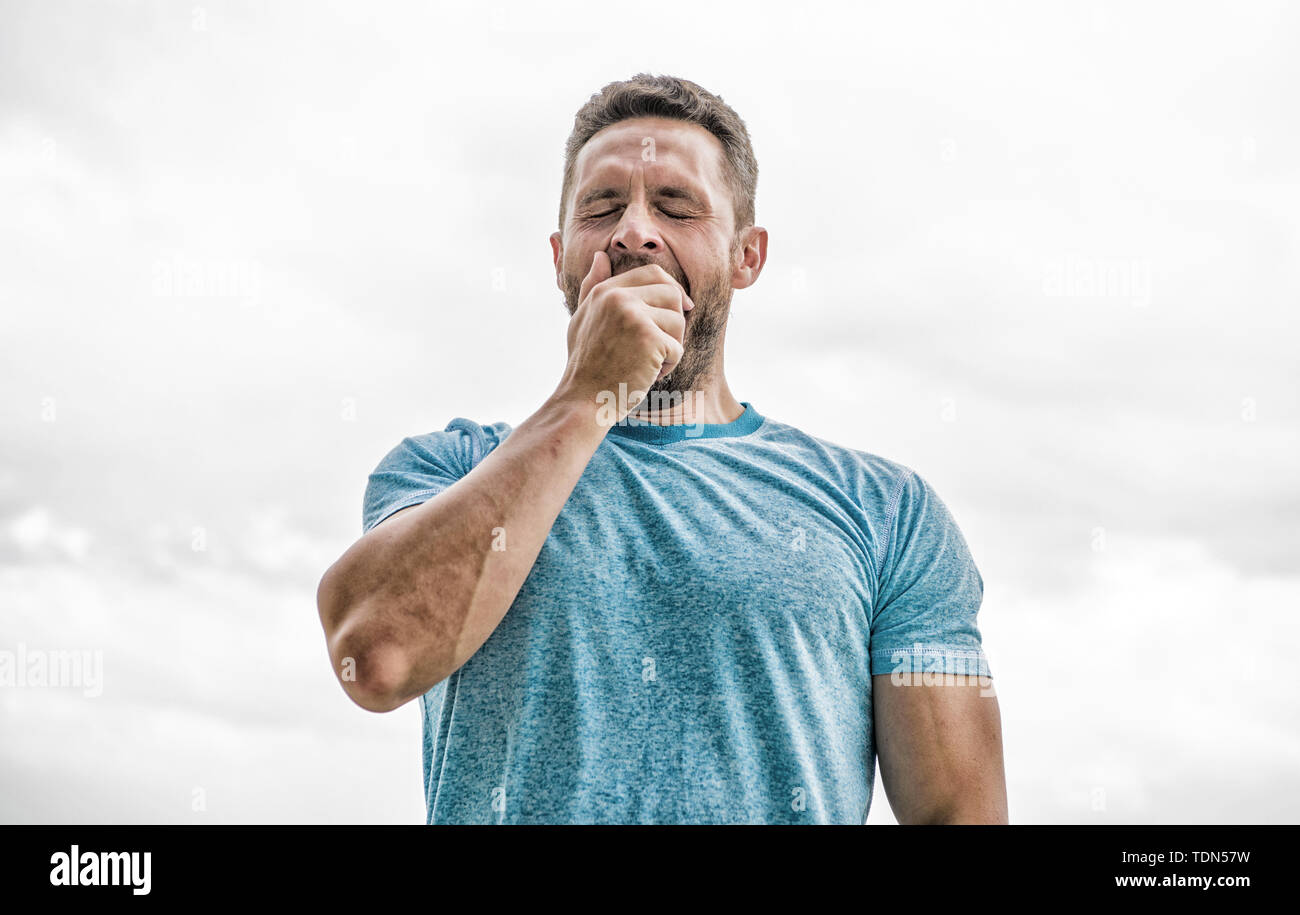 after workout. man athlete in blue sport tshirt. sportswear fashion. yawning  muscular male with beard. sleepy man isolated on white. sportsman with  athletic body. coach in fitness gym. wakeup morning Stock Photo -