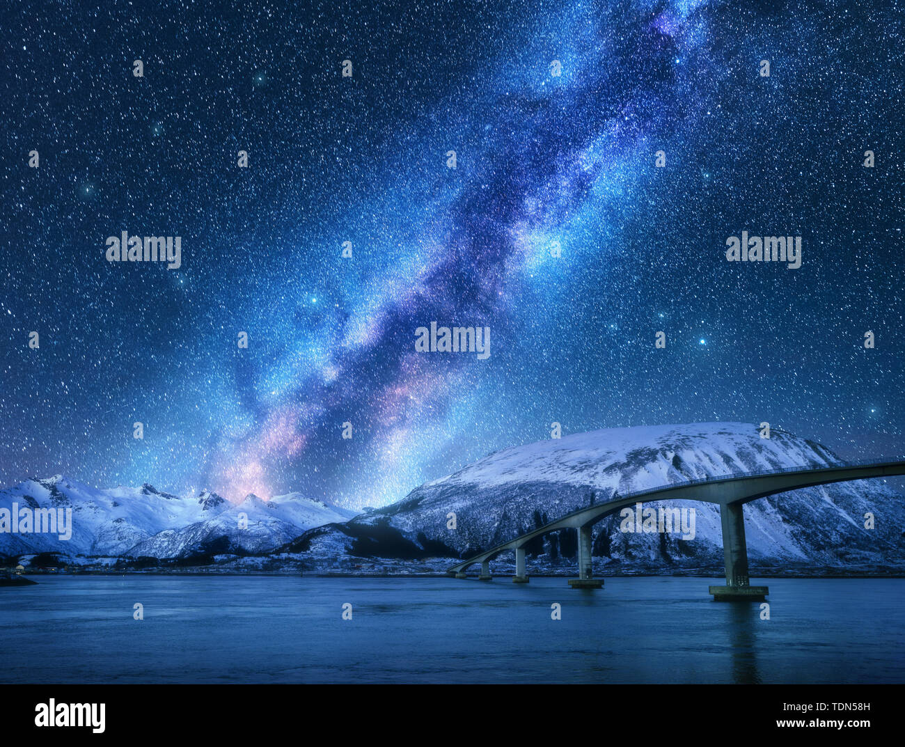 Bridge and starry sky with Milky Way over snow covered mountains Stock Photo