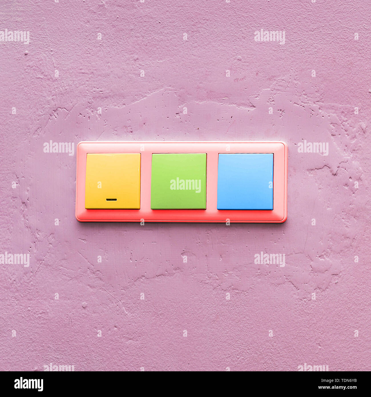 Multicolored light switches on a pink wall. Fashionable colorful