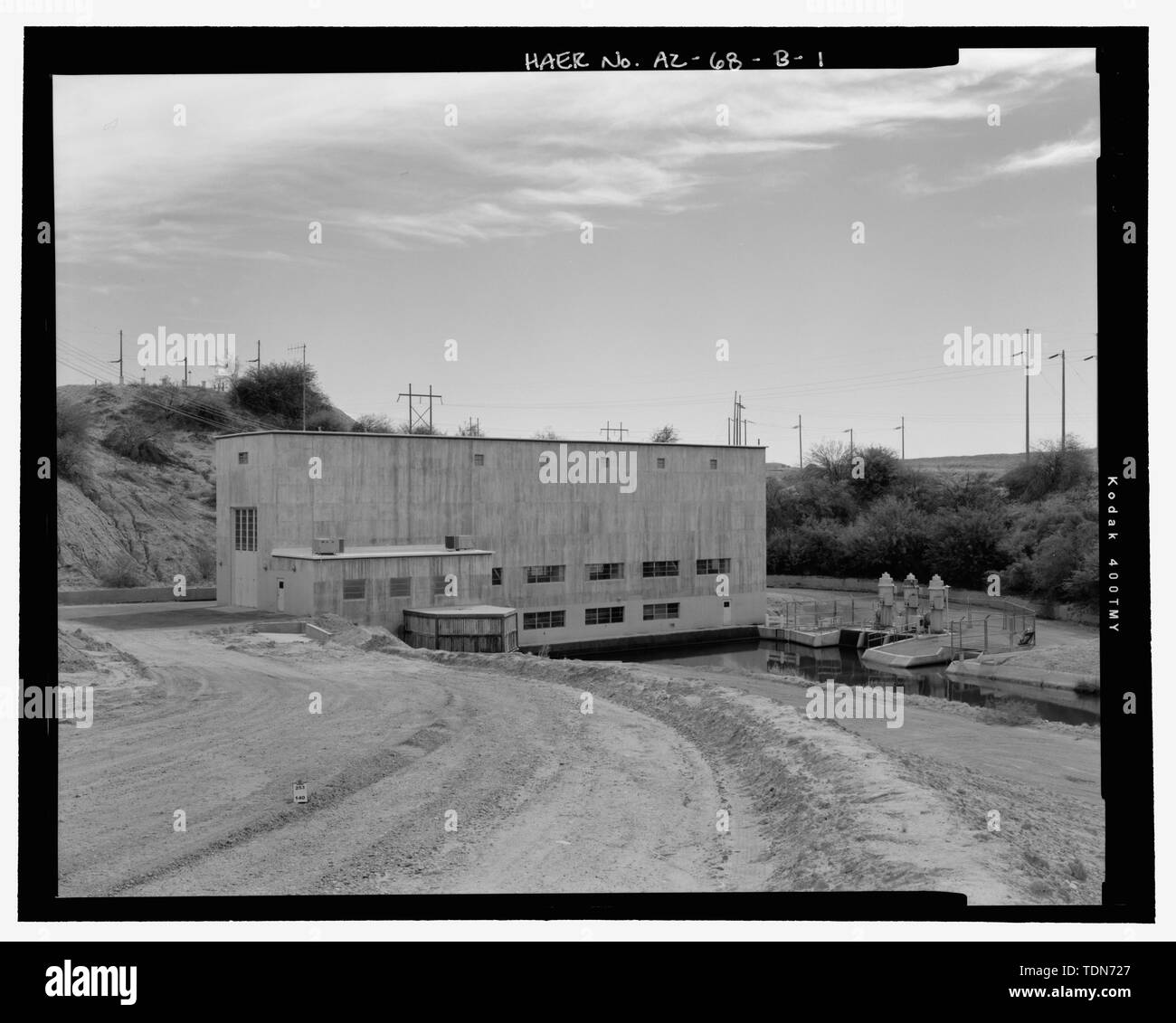 Perspective view, showing west front and north side, with ca. 1974-1975 outdoor regulatory pumps at right, and hydraulic gate check cylinders on the afterbay structure on the crest of the hill in left background - Wellton-Mohawk Irrigation System, Pumping Plant No. 2, Bounded by Interstate 8 to south, Wellton, Yuma County, AZ Stock Photo