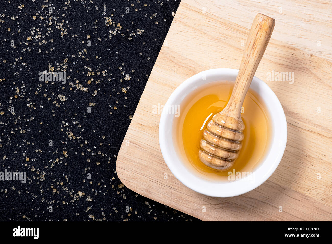 Wooden honey dipper with fresh honey in white plate Stock Photo