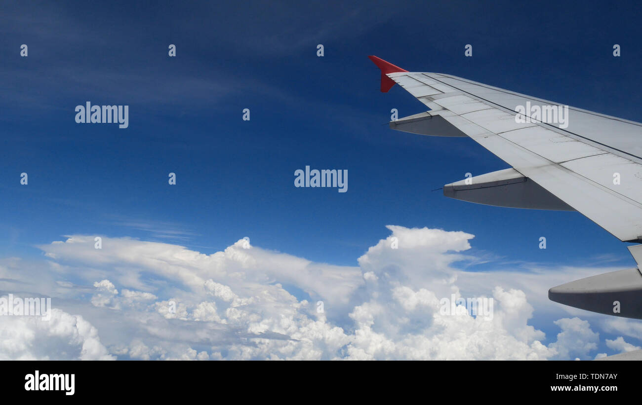 airplane flight. wing of an airplane flying above the white clouds and blue sky. beautiful aerial view from the window of the plane on travelling time Stock Photo