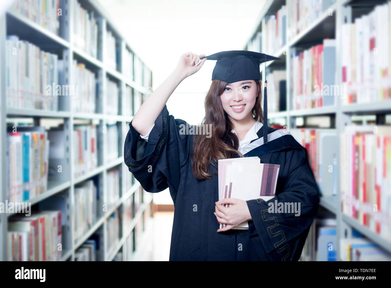 Asian beautiful female student holding book in library Stock Photo - Alamy