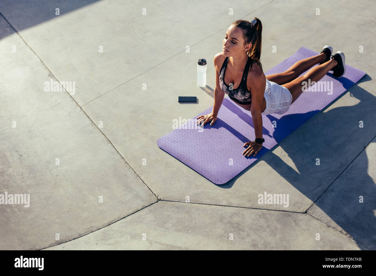 Sports woman practising yoga outdoors. Female in sportswear doing yoga stretches workout in morning. Stock Photo