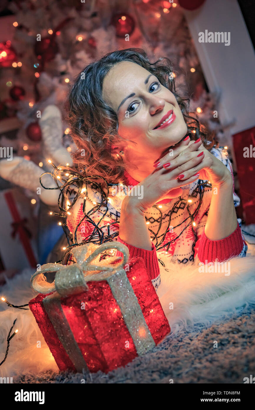 a young woman with gifts in front of christmas tree Stock Photo
