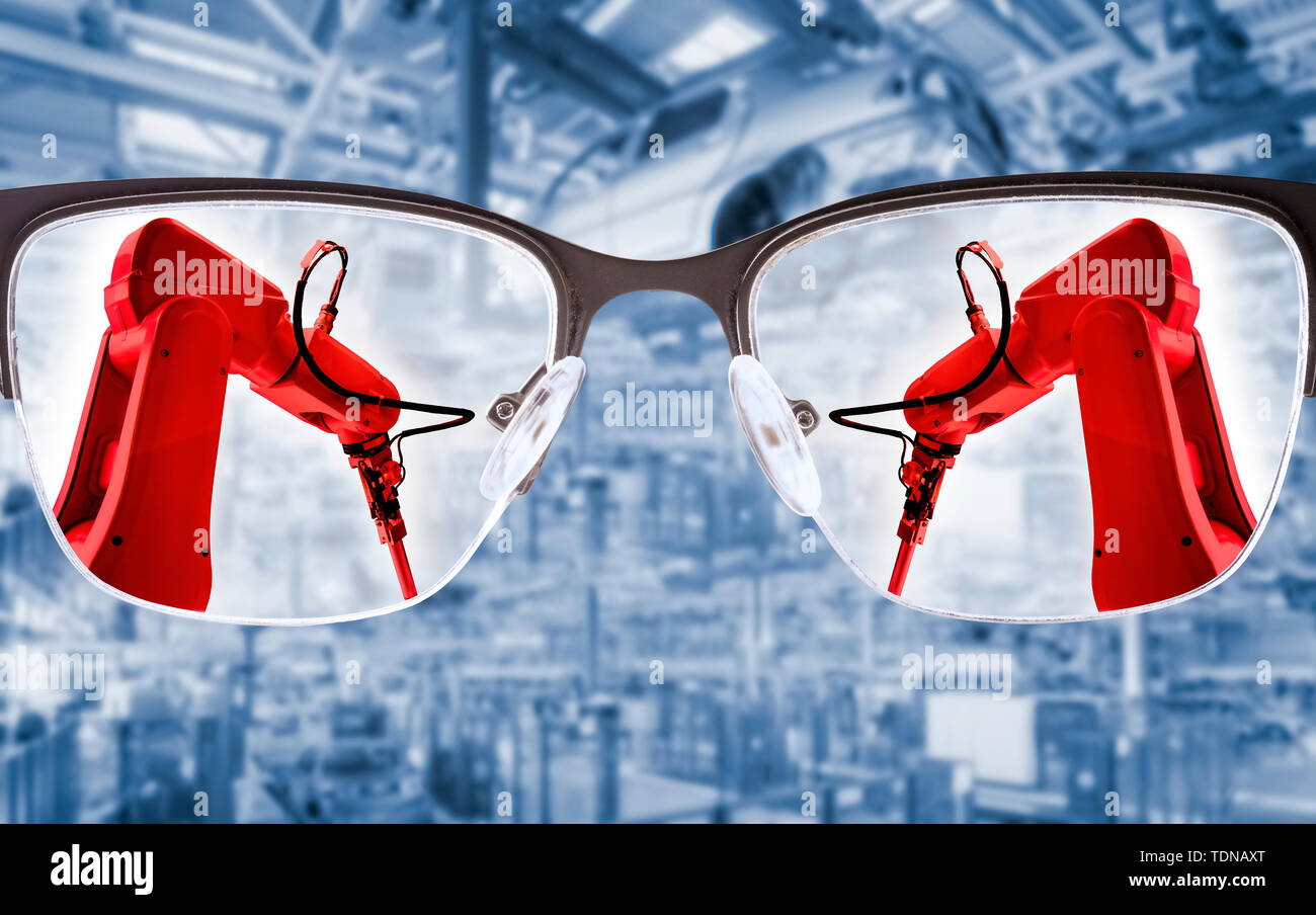 Glasses focus on industrial robots with production hall in the background Stock Photo