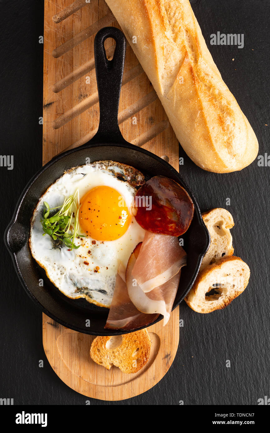 Food Breakfast concept fried egg in skillet iron pan with flax sprouts and bacon with copy space Stock Photo