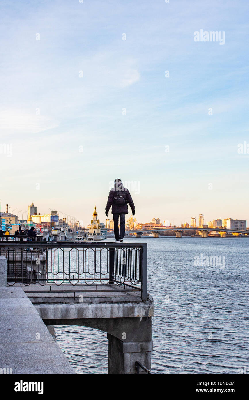 KIEV, UKRAINE - FEBRUARY 2019. The desire to feel adrenaline. The guy walks along the railing on the edge of a cliff, above the river. Stock Photo