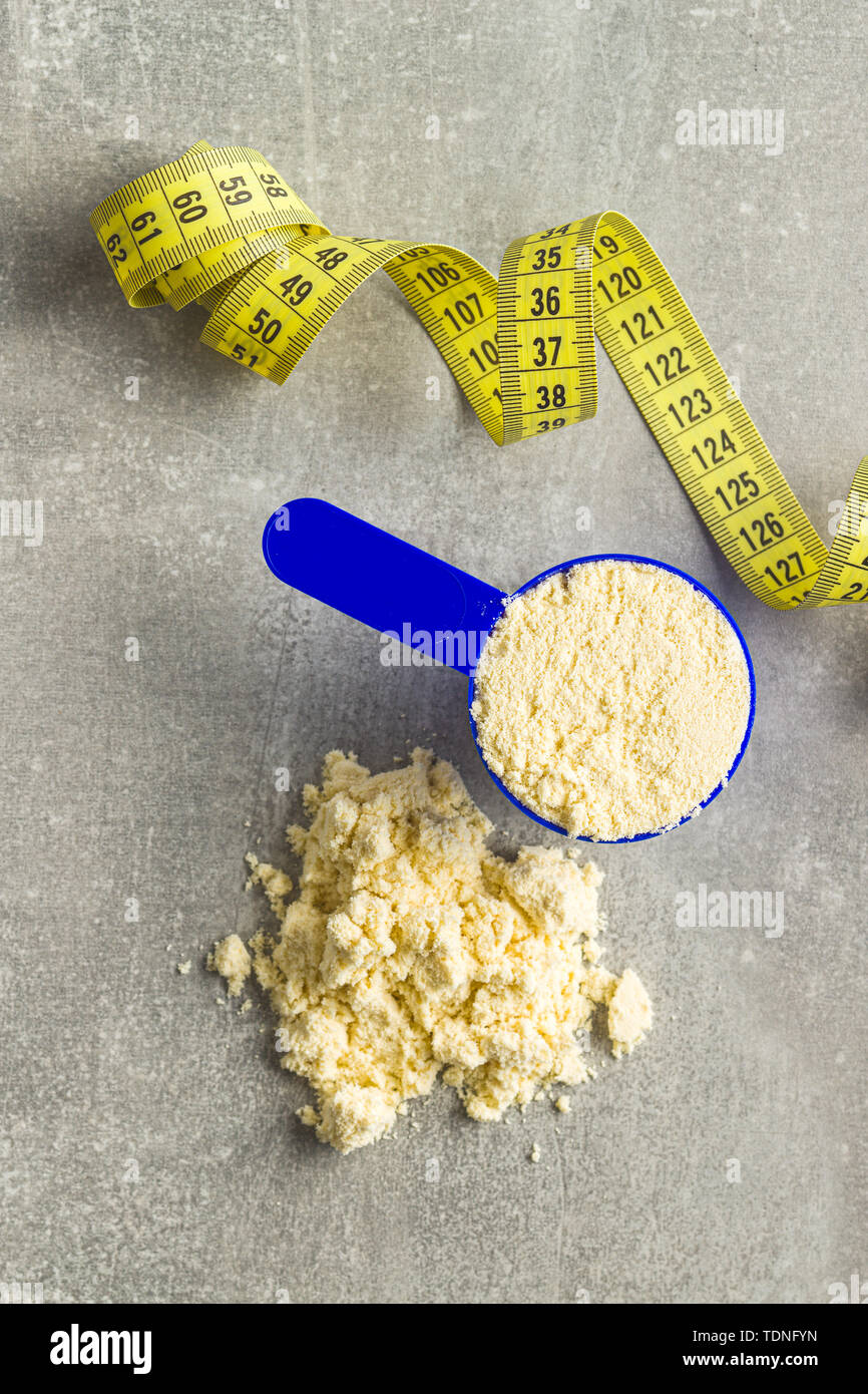 Whey protein powder in scoop and measuring tape. Top view Stock Photo
