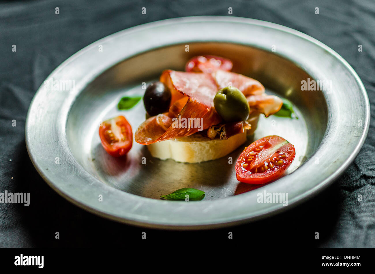 Spanish tapas sandwich with jamon ham, olives, cherry tomatoes, and