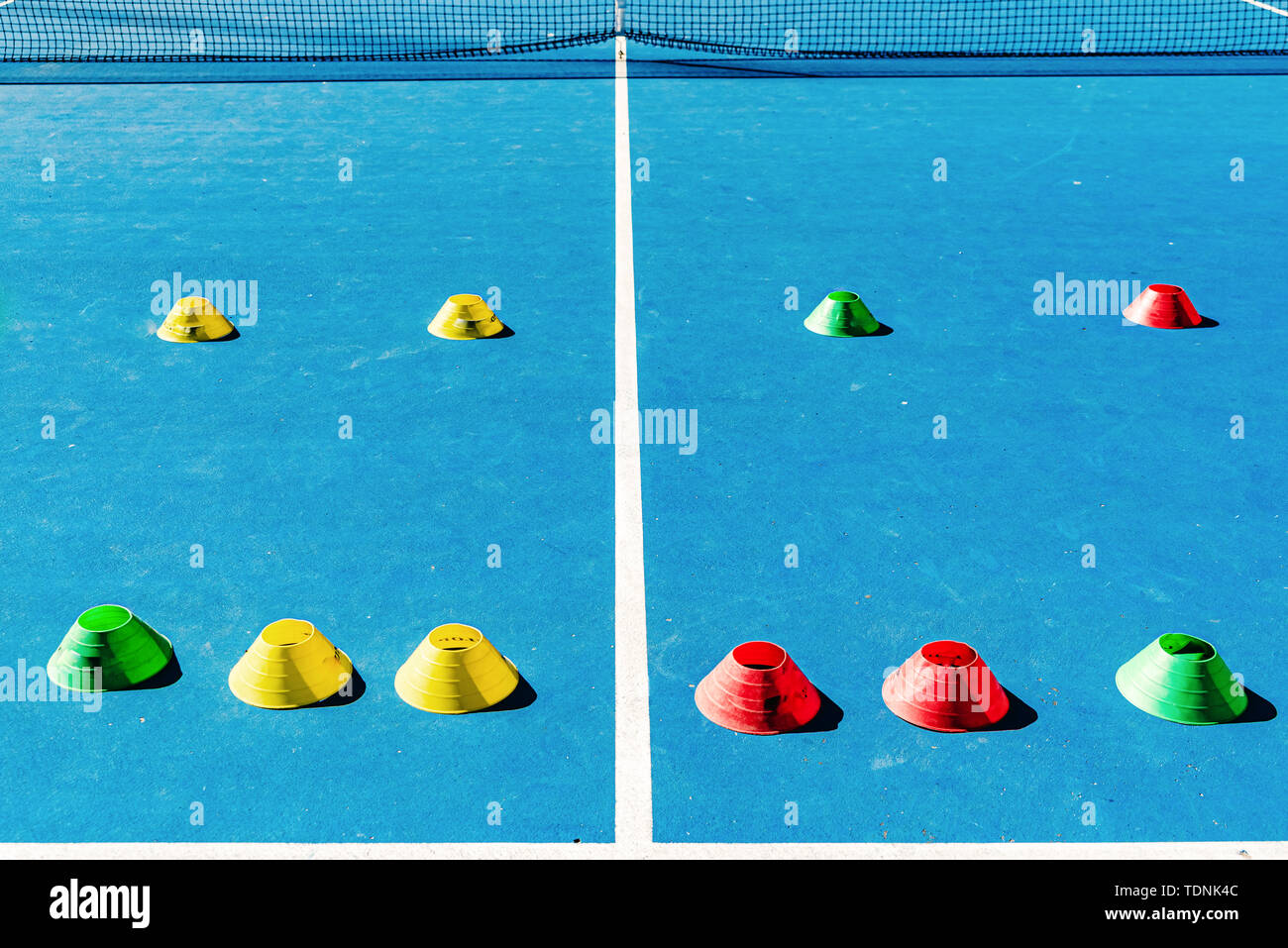 Colorful plastic cones on a blue cement tennis court with white lines