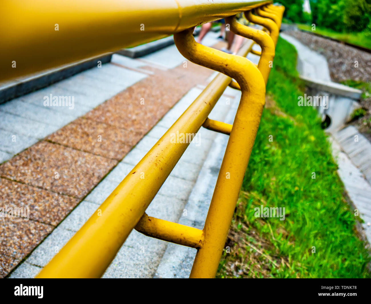 View on a rusty yellow railing of a sidewalk on a sunny day Stock Photo ...