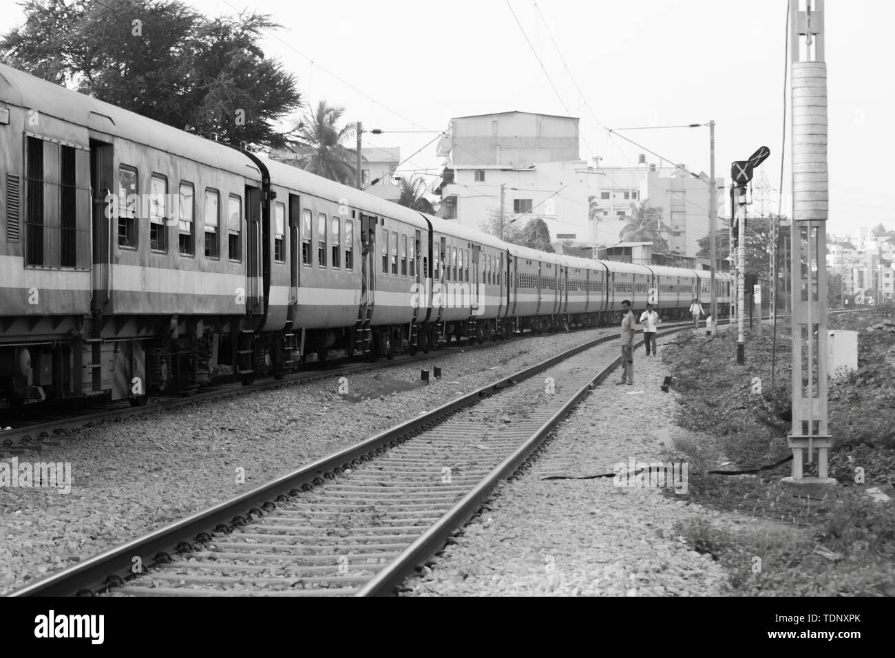 BANGALORE INDIA June 1, 2019 :Monochrome image of People standing on edge of the staircase steps of moving Train at Bengaluru due to non availablity o Stock Photo