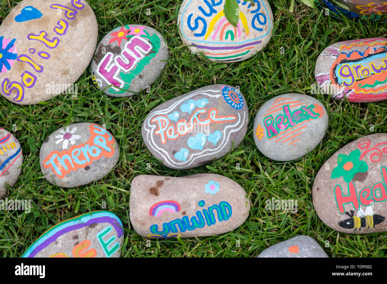 Childrens hand painted words on pebbles on a garden mental health therapy display at a flower show. UK Stock Photo
